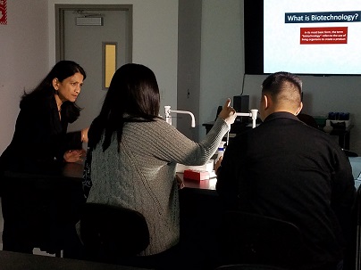 A female instructor overseeing students a laboratory station